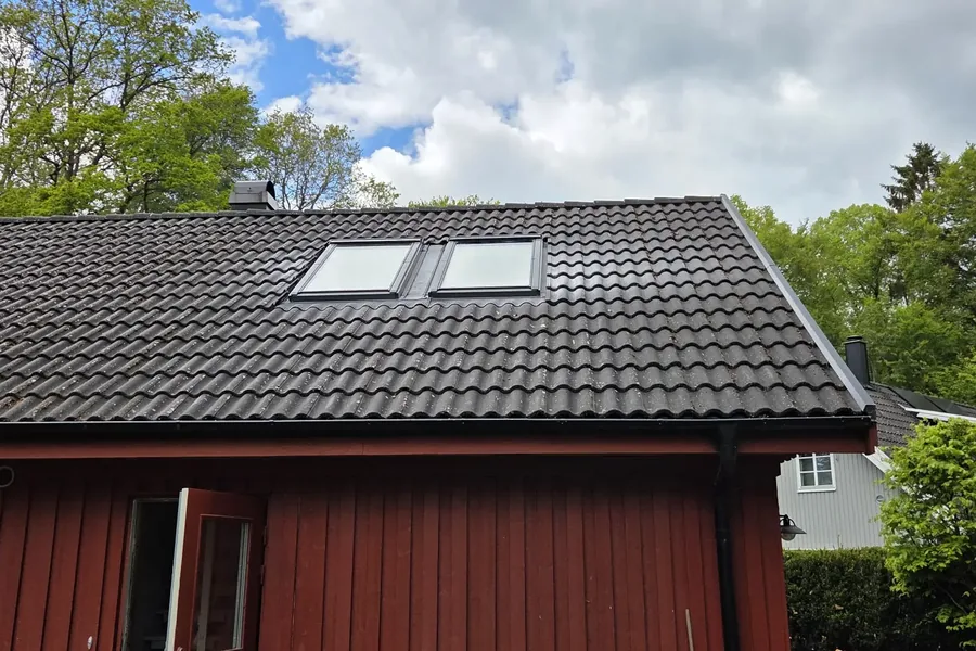 Två takfönster monterade i ett mörkt tak med takpannor